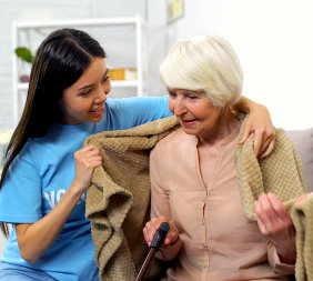 caregiver giving blanket to a senior woman