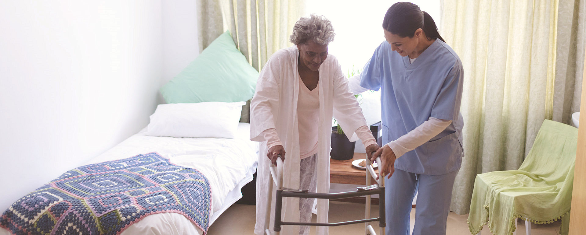 caregiver helping senior woman walk with her walker