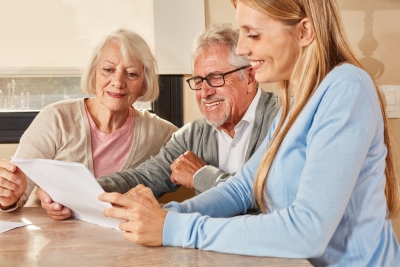 senior couple and female caregiver looking at the paper