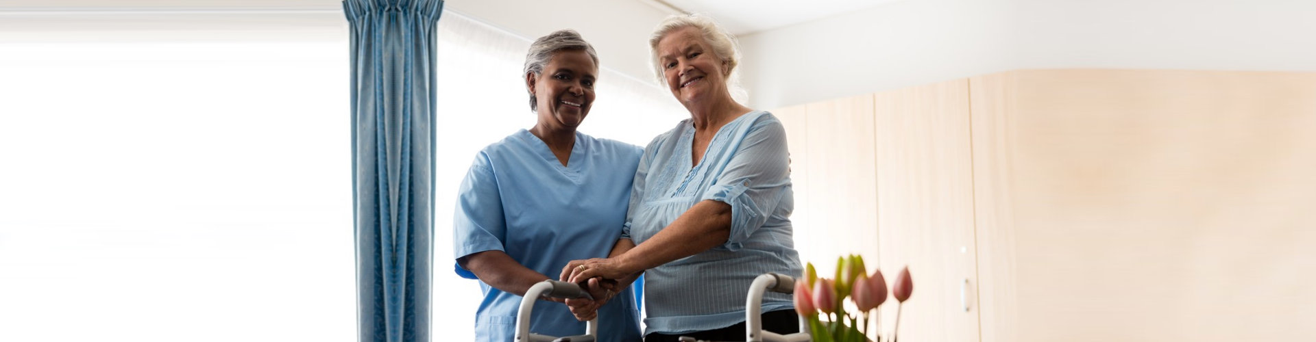 caregiver helping senior woman walk with her walker